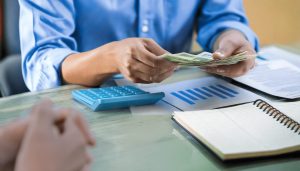 ファクタリングによる資金調達の説明を受けながら現金を受け取るビジネスマンの手元