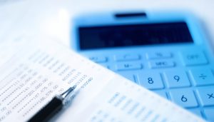 健全な経営に欠かせない売掛金の管理として、仕訳や入金確認などの会計処理を通帳と電卓で行い、資金繰りの安定化を図る様子