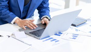 PCや資料のグラフを見ながら、売上債権の勘定科目を管理し、資金繰りの悪化を防ぐために売上債権回転率を分析する担当者