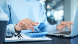 事業に必要な運転資金の計算方法を用い、資金繰りのために電卓で所要運転資金を計算する担当者