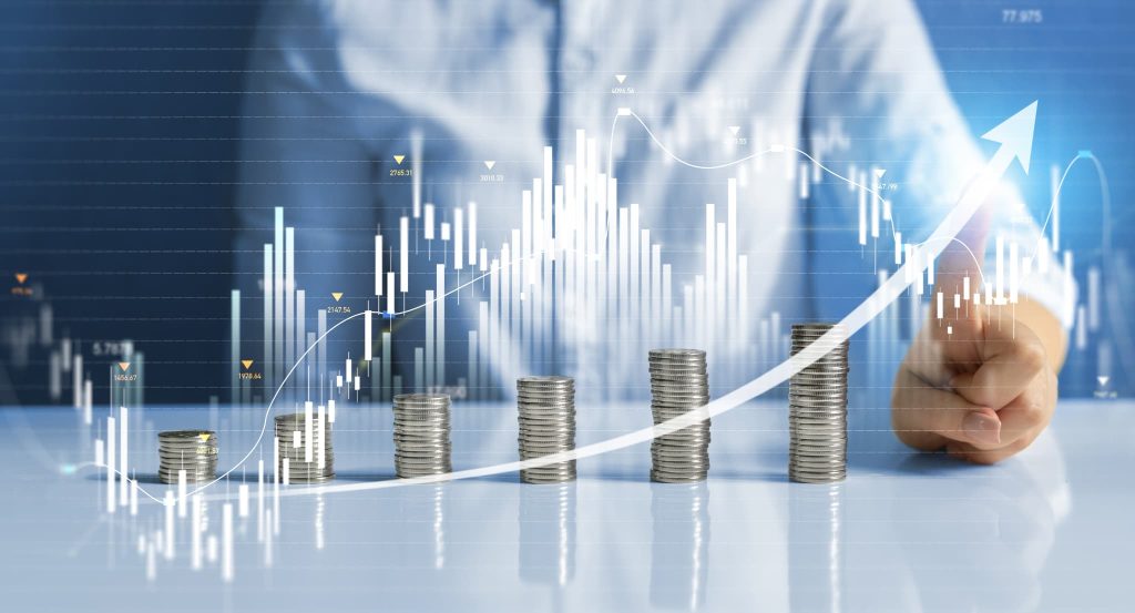 積み上げられたコインと上昇するデジタルチャートを指さす人物。返済不要の資金調達を活用することで負債リスクを抑え、経営を右肩上がりの成長軌道に乗せる成功イメージ