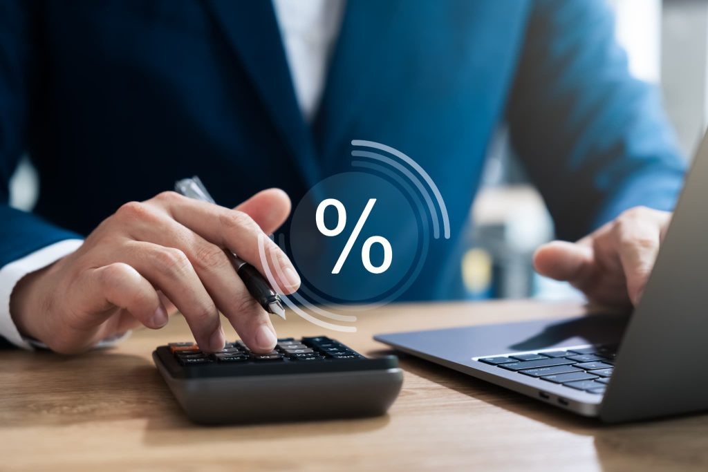 スーツを着た人物が電卓を操作してファクタリングの手数料率や掛け目を計算している様子とパーセンテージを表すアイコン