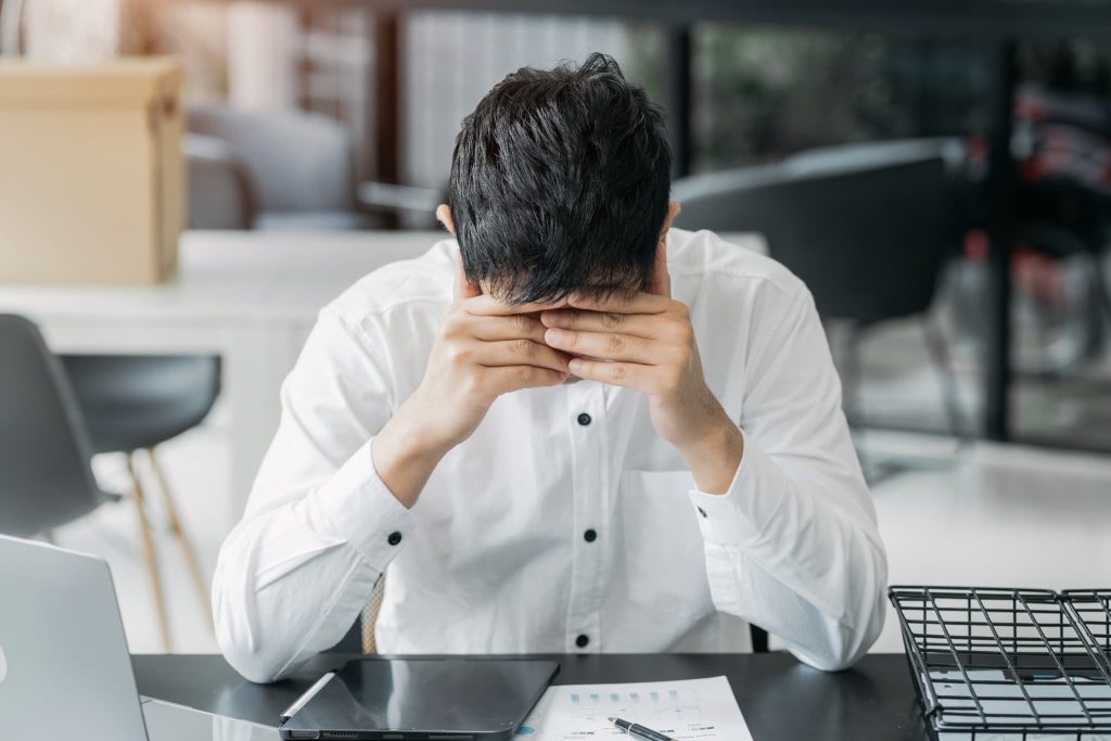 届いた督促状の支払いや資金繰りの目処が立たずデスクで頭を抱えて悩んでいる男性