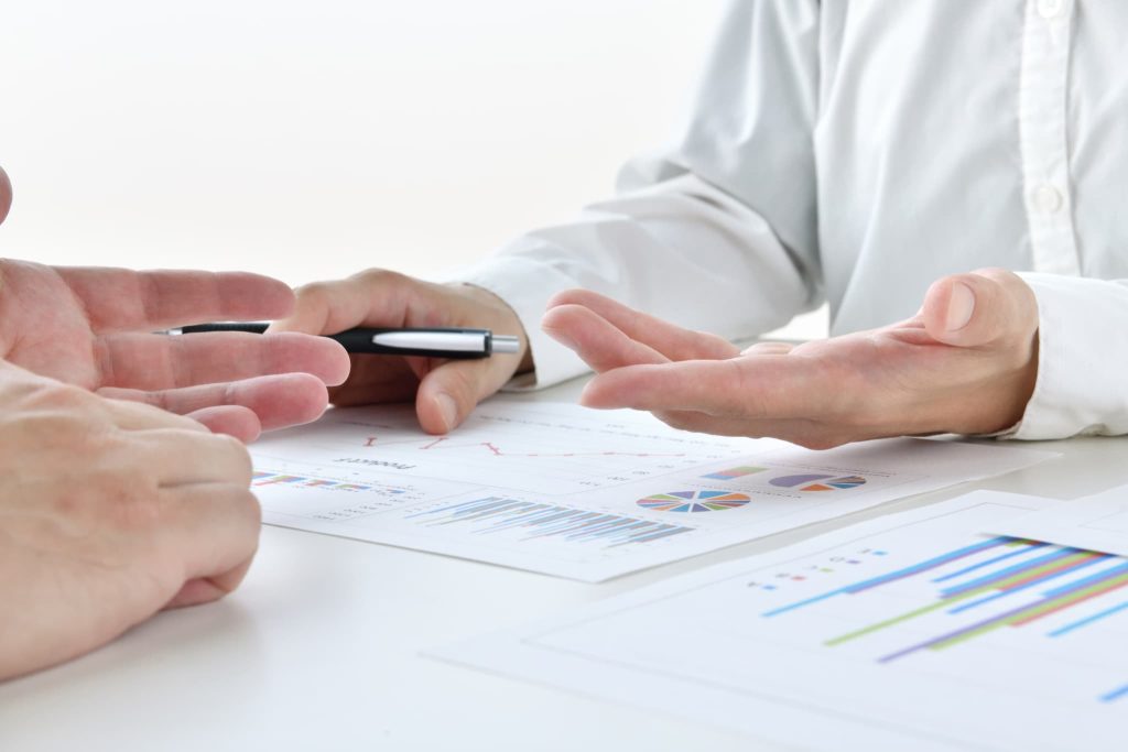 日本政策金融公庫の担当者と対面で事業計画や返済シミュレーションの資料を確認しながら融資相談を行う様子