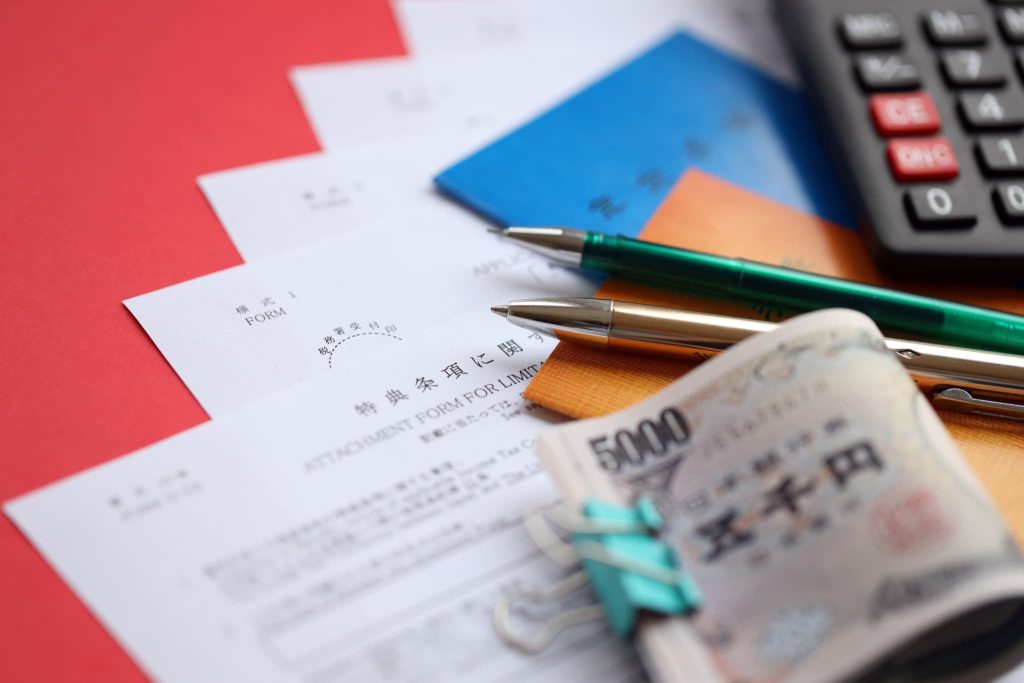 おすすめの補助金の申請手続きに必要な書類や通帳および現金などの資金を用意しているテーブルの上