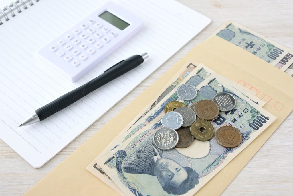 補助金と助成金の支給金額の違いや必要な自己資金を把握するために現金と電卓を並べたイメージ
