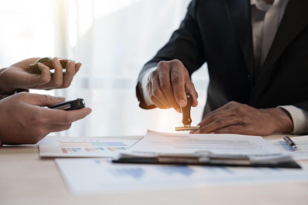 契約書に判子を押して契約を締結する様子で、担保設定や融資など具体的な資金調達方法の手続きを進めているビジネスシーン
