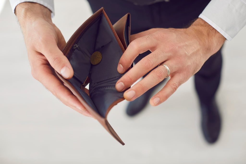 開業資金の不足や資金繰りの不安を象徴する中身が空に近い財布を確認しているビジネスマン