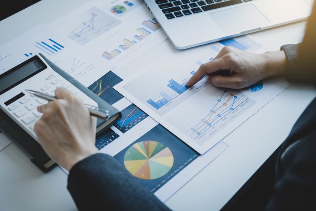 複数のグラフ資料と電卓を用いて経営数値を分析している手元。資金調達とは、正確な財務状況の把握と説得力のある事業計画に基づいて行われるものであることを示唆
