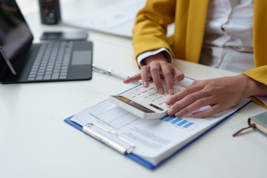 経営の健全化を目指して電卓とグラフ資料を使いながら経費の内訳を見直し固定費削減を検討する女性