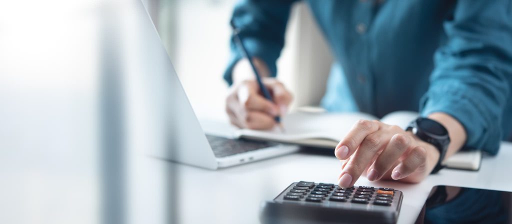 小規模事業者持続化補助金の申請に必要な対象経費の算出や事業計画の収支計算を電卓で行っている手元