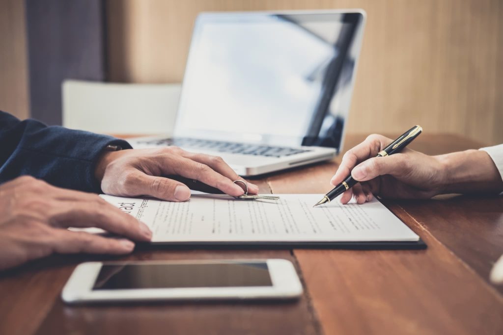 債権とは契約に基づき発生する権利であるため内容を入念に確認して契約書に署名をしている手元