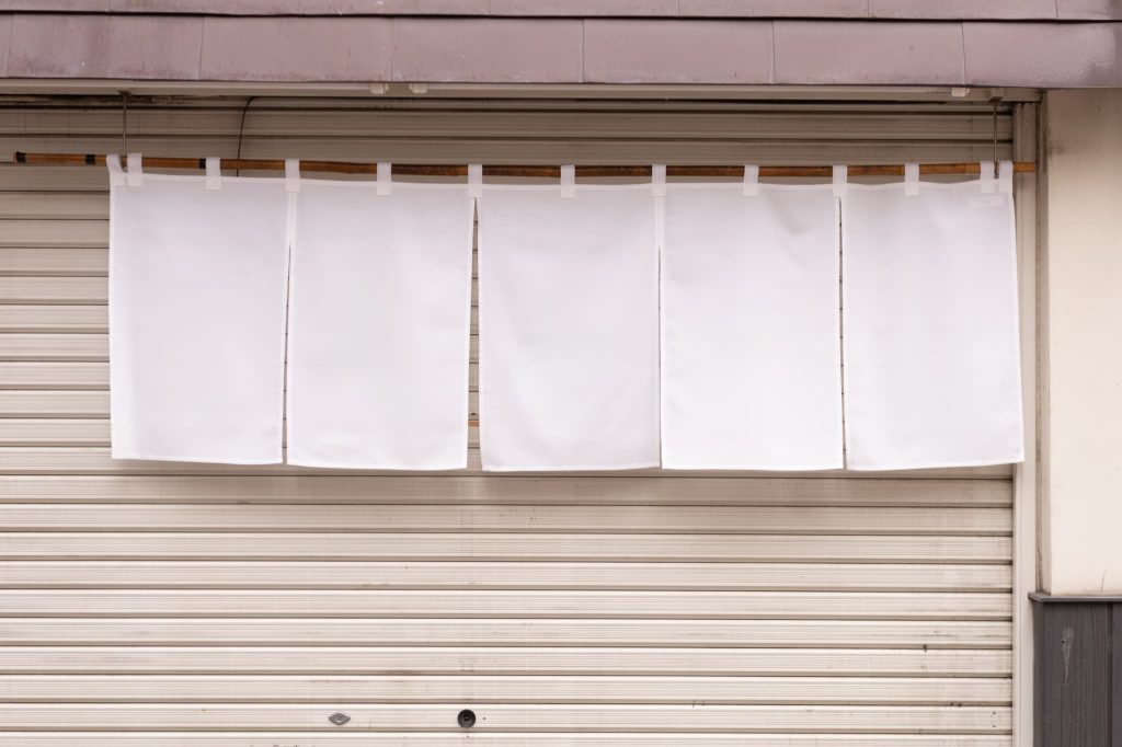 利益が出ていても資金ショートにより閉店せざるを得ない黒字倒産をイメージさせるシャッターの閉まった店舗