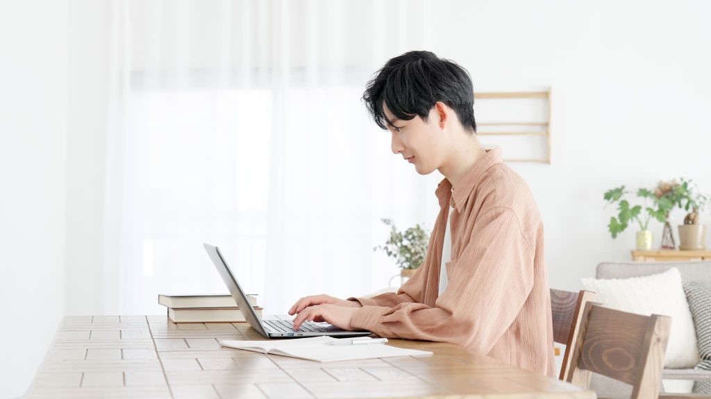 自宅でノートパソコンに向かいオンライン完結型のファクタリング申請や電子手形の手続きを行っている男性の横顔