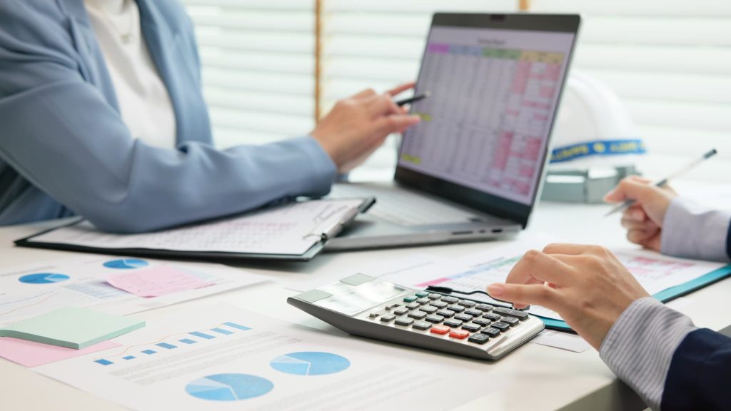 黒字倒産対策として資金繰り表や決算書をパソコンで確認しながら税理士と打ち合わせを行う経営者