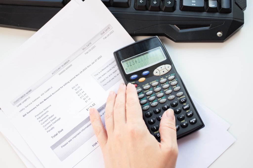 ファクタリングの利用に伴う返済額や未払いの請求書を電卓を使って正確に計算している手元の様子