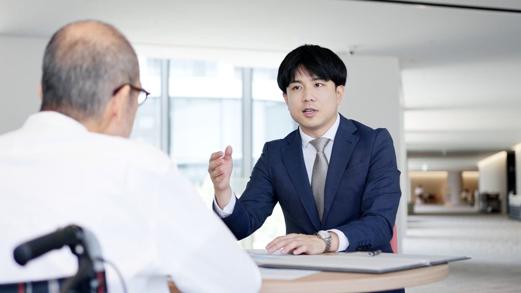 スーツを着た担当者が対面で詳しく説明をしている相談風景。ビジネスローンの審査基準や即日融資を受けるための条件について専門家に確認している場面