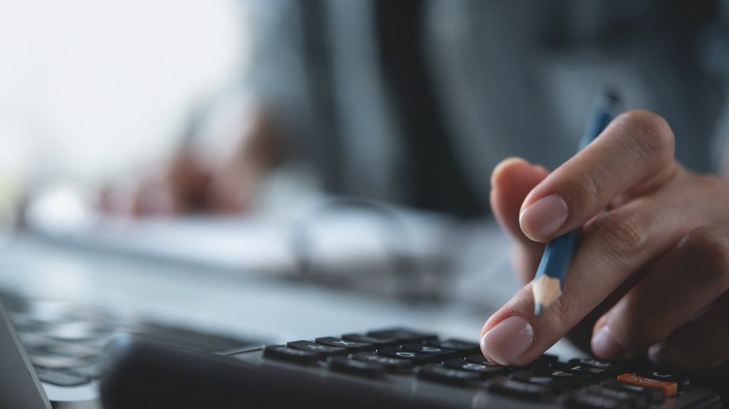 ファクタリングの利用前に返済負担や手数料をシミュレーションするために電卓で計算を行っている様子