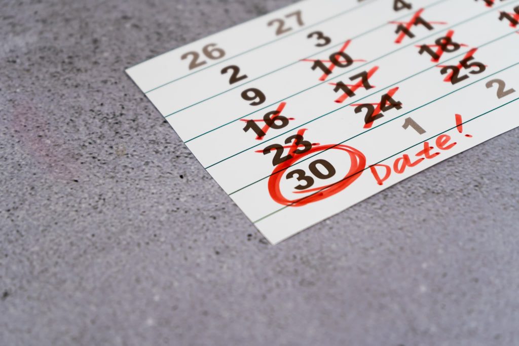 カレンダーの30日の日付に赤い丸印とDateの文字が書き込まれ、支払いサイトの期日や締め日などの重要なスケジュールを管理している状態