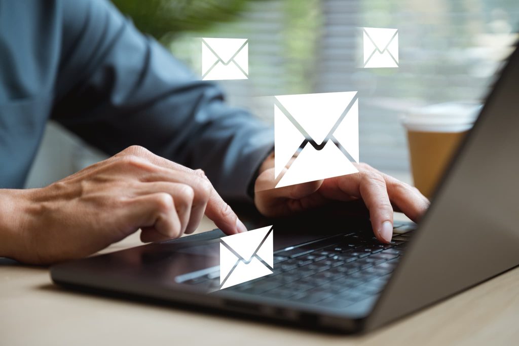 ノートパソコンでビジネスメールを送信する手元と封筒のアイコンのイメージで、支払いサイトに関する連絡や請求書送付の業務を表している