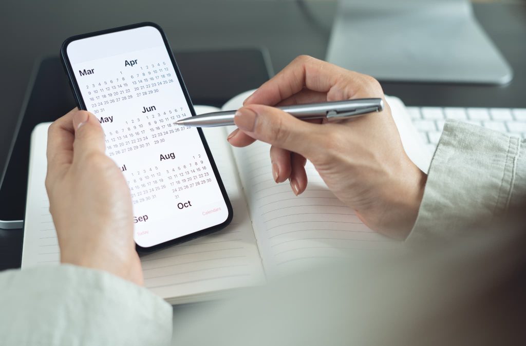 売上債権の回収漏れを防ぐためにスマートフォンと手帳のカレンダーを使って入金期日を管理している様子