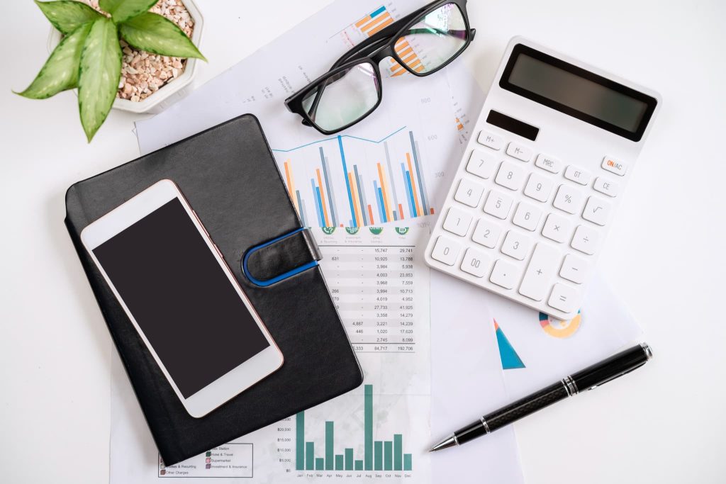 BPSPを利用した際の資金移動や手数料を経理担当者が電卓とスマートフォンで計算している様子