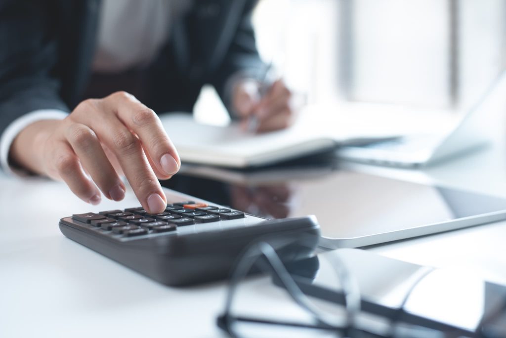 売上債権の入金消込や回収状況を確認するために電卓と書類を使って計算業務を行っている経理担当者