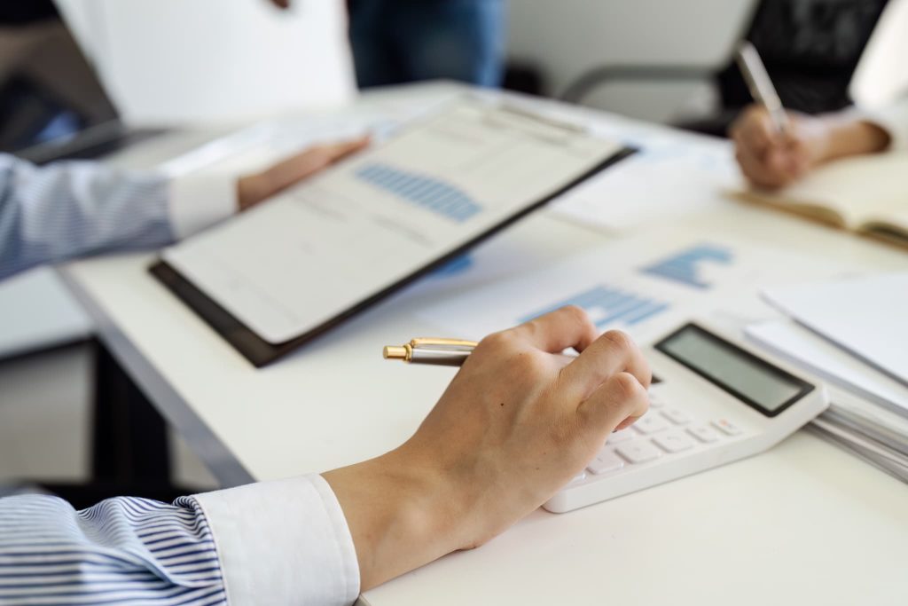 個人事業主がカードローンの利用にあたり事業の資金繰りや返済計画を電卓と決算資料を使って計算している様子