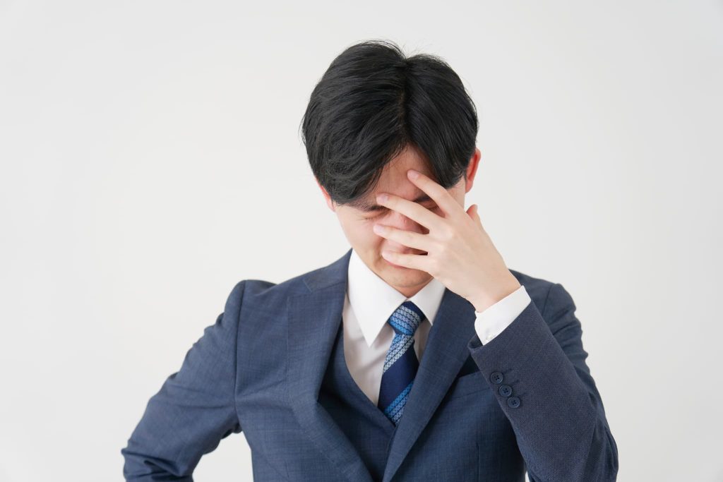 ファクタリングの返済期日に間に合わないなどのトラブルに直面し頭を抱えて苦悩しているビジネスマン