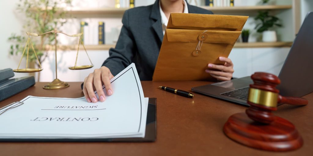 売掛とは信用取引に基づく契約であることを示す天秤と木槌およびデスクで契約書の内容を確認している様子