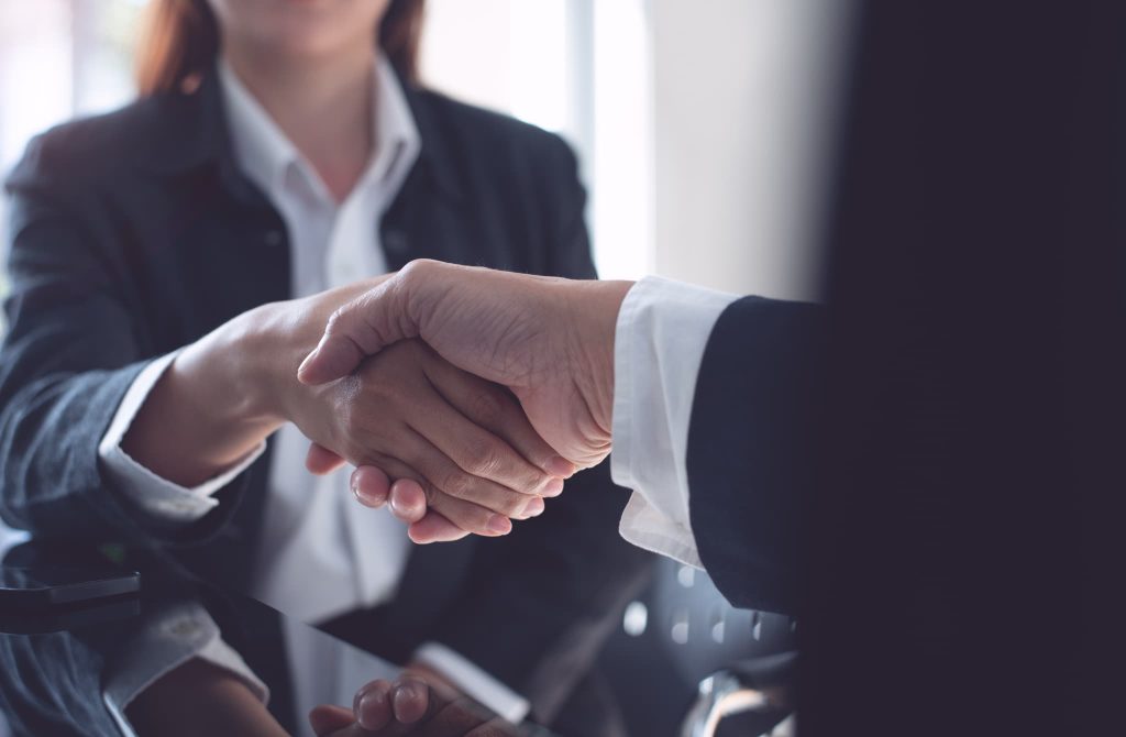 2社間ファクタリングや3社間ファクタリングの契約が成立し信頼の証として握手を交わすビジネスマン