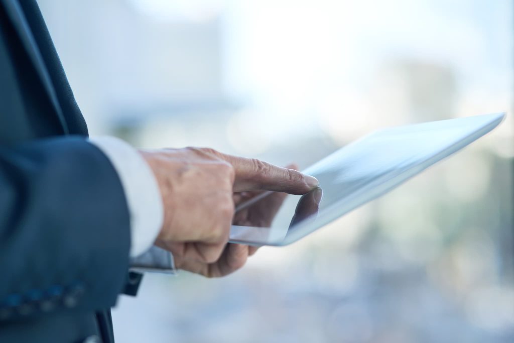 中小企業の資金調達手続きを効率化するファクタリングサービスやオンライン融資をタブレットで操作する手元のアップ