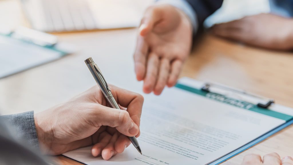 契約書にペンで署名しようとしている手元。ビジネスローン契約前にメリットだけでなくデメリットや返済条件を十分に確認する重要性