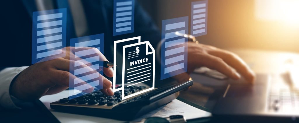 デスクで電卓を叩く手元とINVOICEと書かれた請求書のアイコン。請求書払いとはどのような業務かを表す経理処理のデジタルイメージ