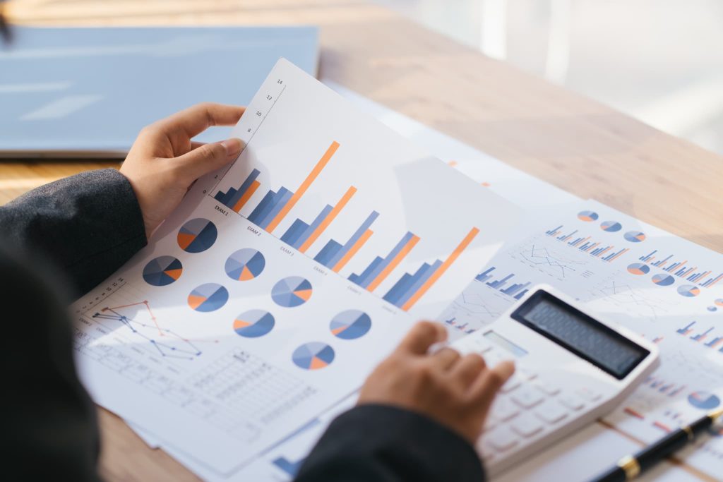 日本政策金融公庫への提出書類作成に向けて事業の収支推移や返済計画をグラフ資料と電卓で計算している手元