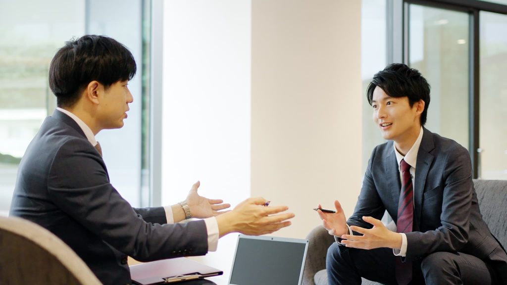 銀行の担当者と借り換え融資の条件や返済計画の見直しについて対面で相談を行っているビジネスマン