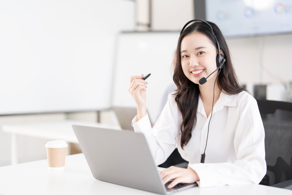 請求書の立替払いサービスに関する問い合わせに笑顔で対応するカスタマーサポートの女性オペレーター