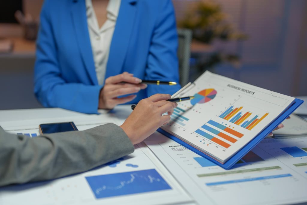 グラフが描かれた経営資料を指差しながらファクタリングを活用した財務改善について担当者と詳細な打ち合わせをしている様子