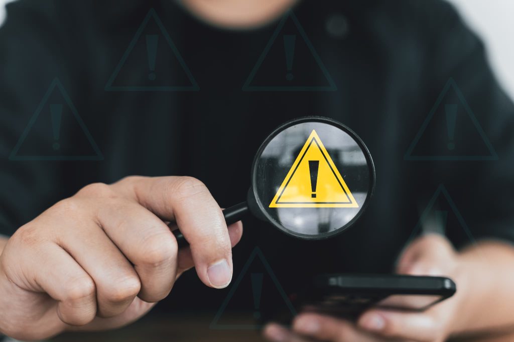 督促状が届く前段階としてスマートフォン上の警告アイコンで支払いの遅延や注意喚起を確認している様子