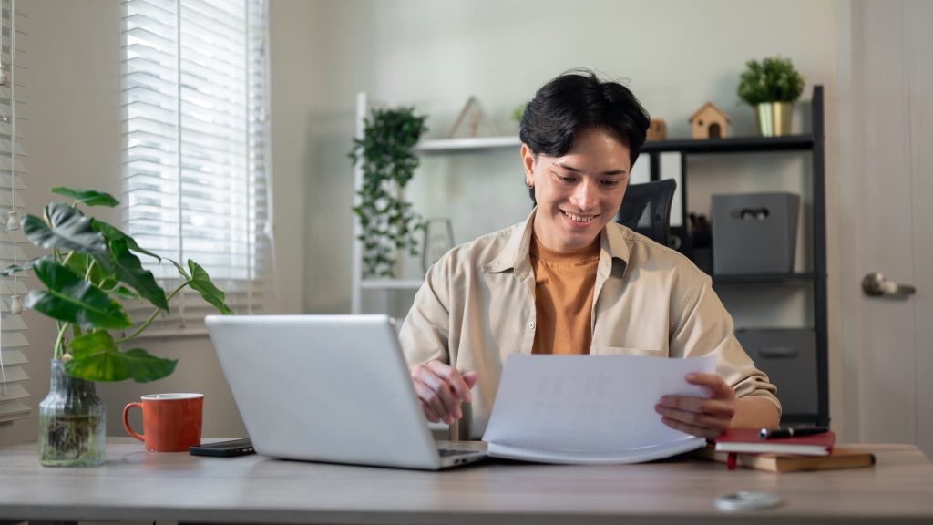 2社間ファクタリングや3社間ファクタリングによる資金調達の手続きを終え書類を見ながら笑顔を見せる男性