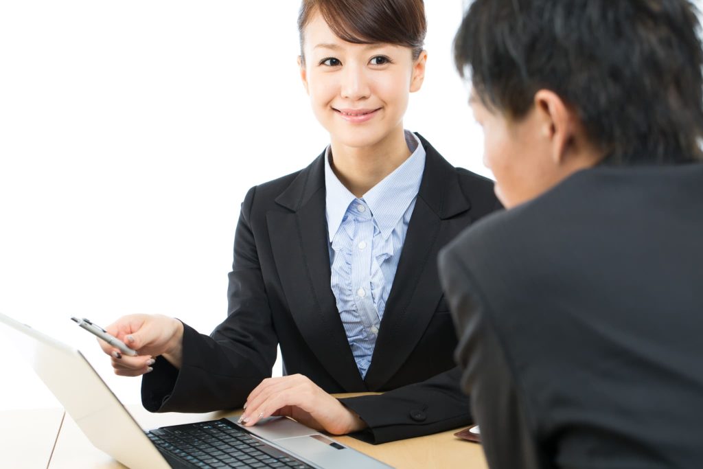 中小企業の資金調達に関する相談窓口で、女性担当者がパソコン画面を見せながら制度融資の仕組みを説明している様子