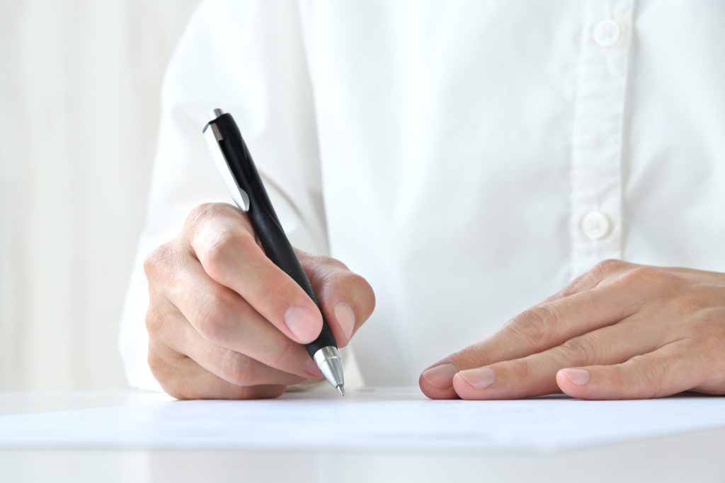 補助金と助成金の違いにより異なる申請書類の記載項目を確認しペンで記入を行っている手元