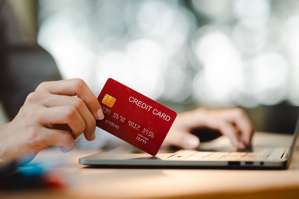 ノートパソコンの前でクレジットカードを持つ手元。請求書立替払いサービスを利用する場面