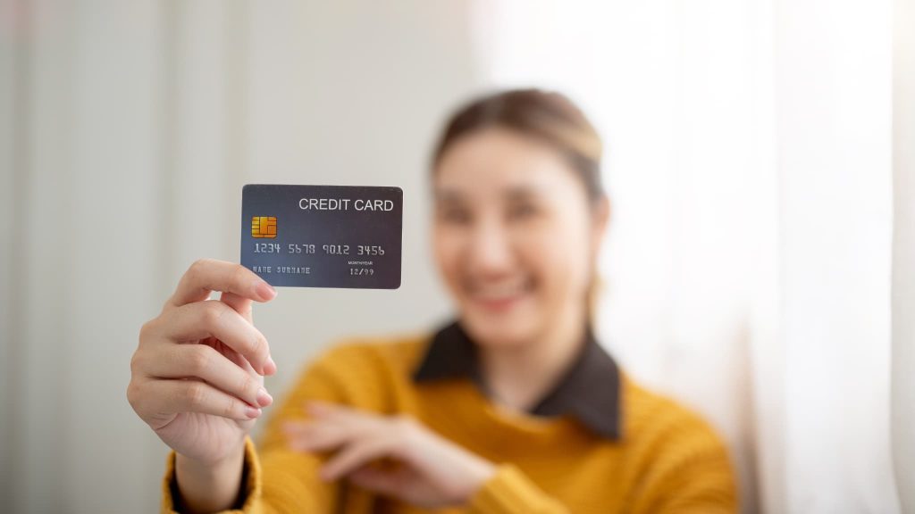 手持ちの法人カードやビジネスカードを使って請求書カード払いサービスが利用できることをアピールしている女性