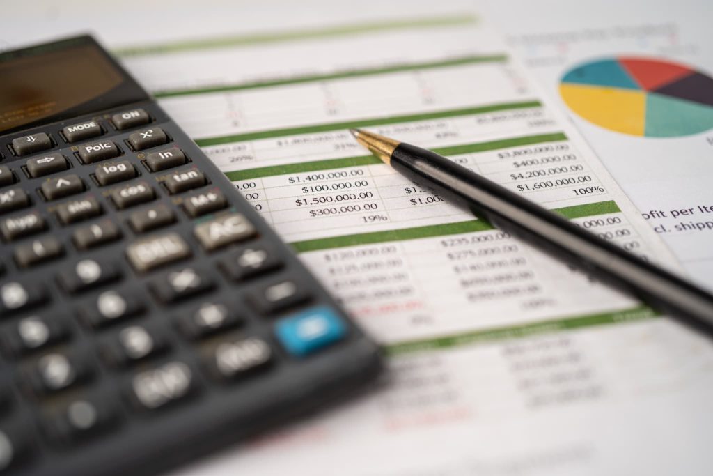 財務データやグラフが印刷された資料と電卓。売掛金とは貸借対照表において流動資産に区分され資金繰りに直結する重要な勘定科目