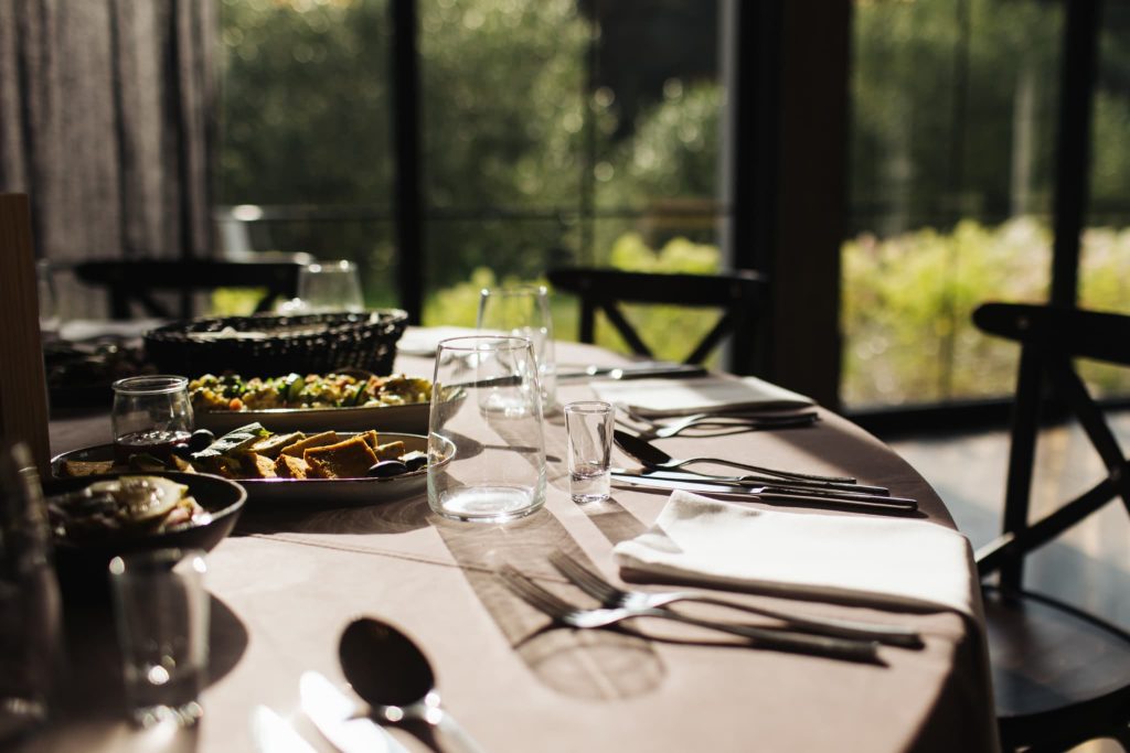 レストランのテーブルに綺麗に並べられた料理とカトラリー。飲食店の開業イメージや、内装・設備投資のための資金調達を連想させるシーン