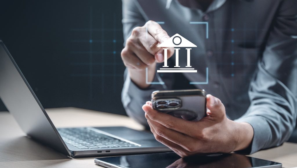 スマートフォン上の銀行アイコンを指差す手元。当座貸越とは銀行などの金融機関と契約を結ぶことで利用可能になる融資枠であることを表すイメージ