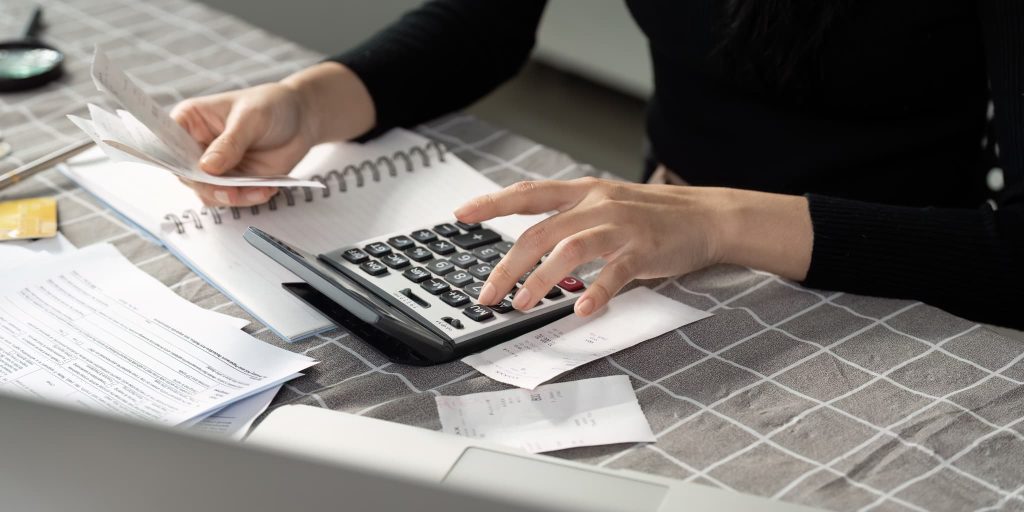 売上債権の入金額と請求金額にズレがないか領収書や伝票を照らし合わせて電卓で集計している様子