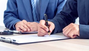 2024年3月に終了した新創業融資制度に代わり、日本政策金融公庫の新規開業・スタートアップ支援資金を利用して無担保・無保証で事業資金を調達するための契約書に署名する様子