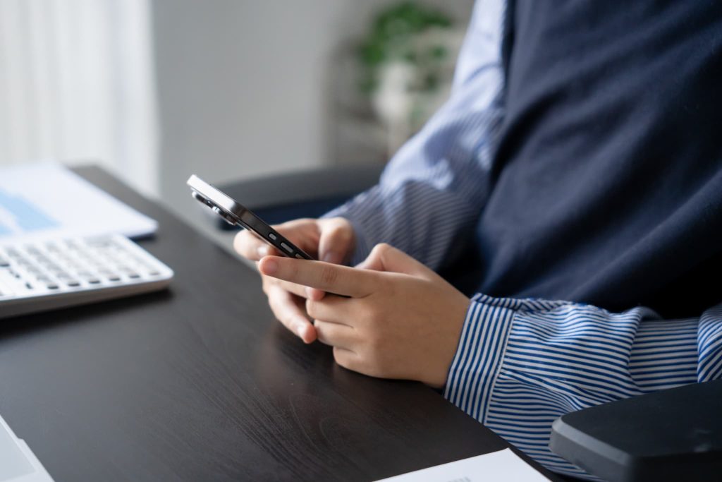 営業キャッシュフローの最新データやキャッシュレス決済の入金状況をスマートフォンで確認するデスクワークの風景